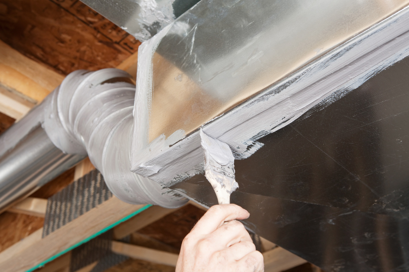 Duct sealing with mastic sealant closing leaks in ductwork for improved energy efficiency.