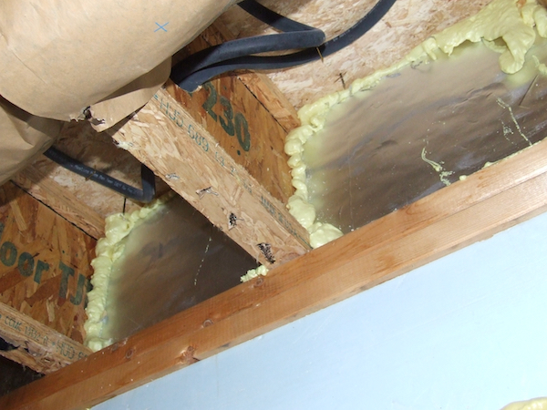 Rim joist and foundation sealing with spray foam insulation stopping cold-floor drafts.