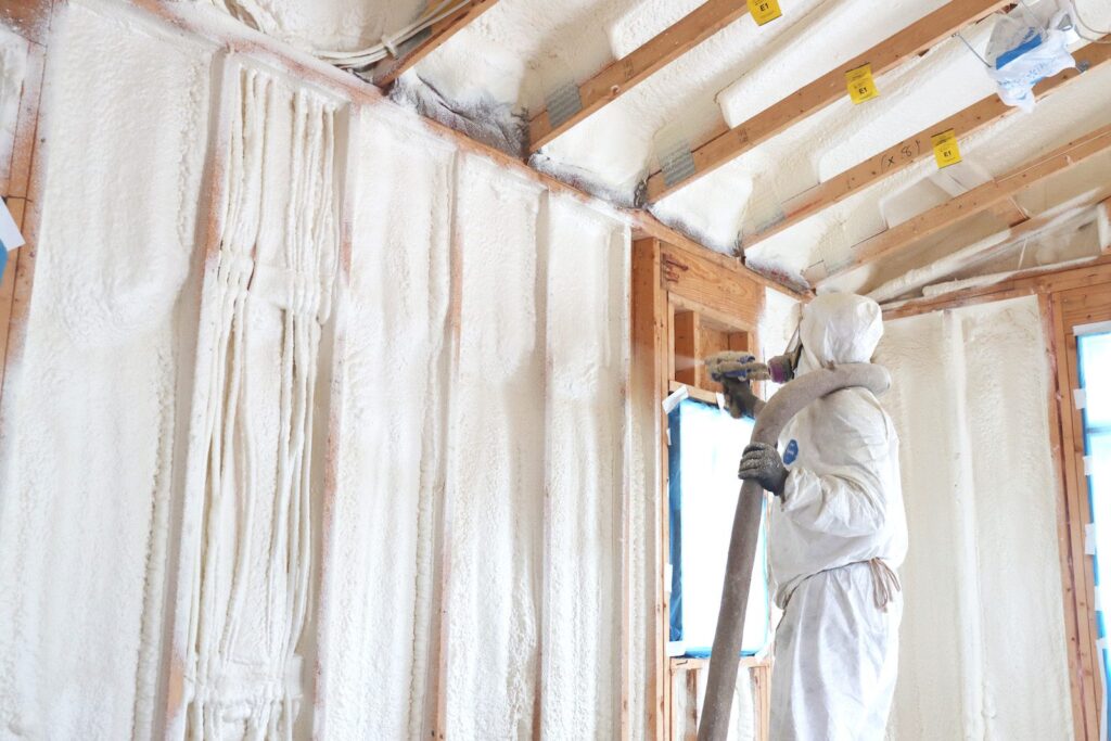 Injection wall foam insulation filling wall cavity, worker applying foam during retrofit installation.